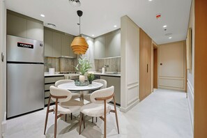 A modern kitchen with a built-in refrigerator, a round dining table with chairs, and a hanging pendant light. - Cloud Tower 2BR · Pool & Gym · JVT (Dubai)