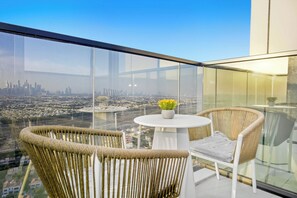 A high-rise balcony with a city view, a round table, and wicker chairs. - Cloud Tower 2BR · Pool & Gym · JVT (Dubai)