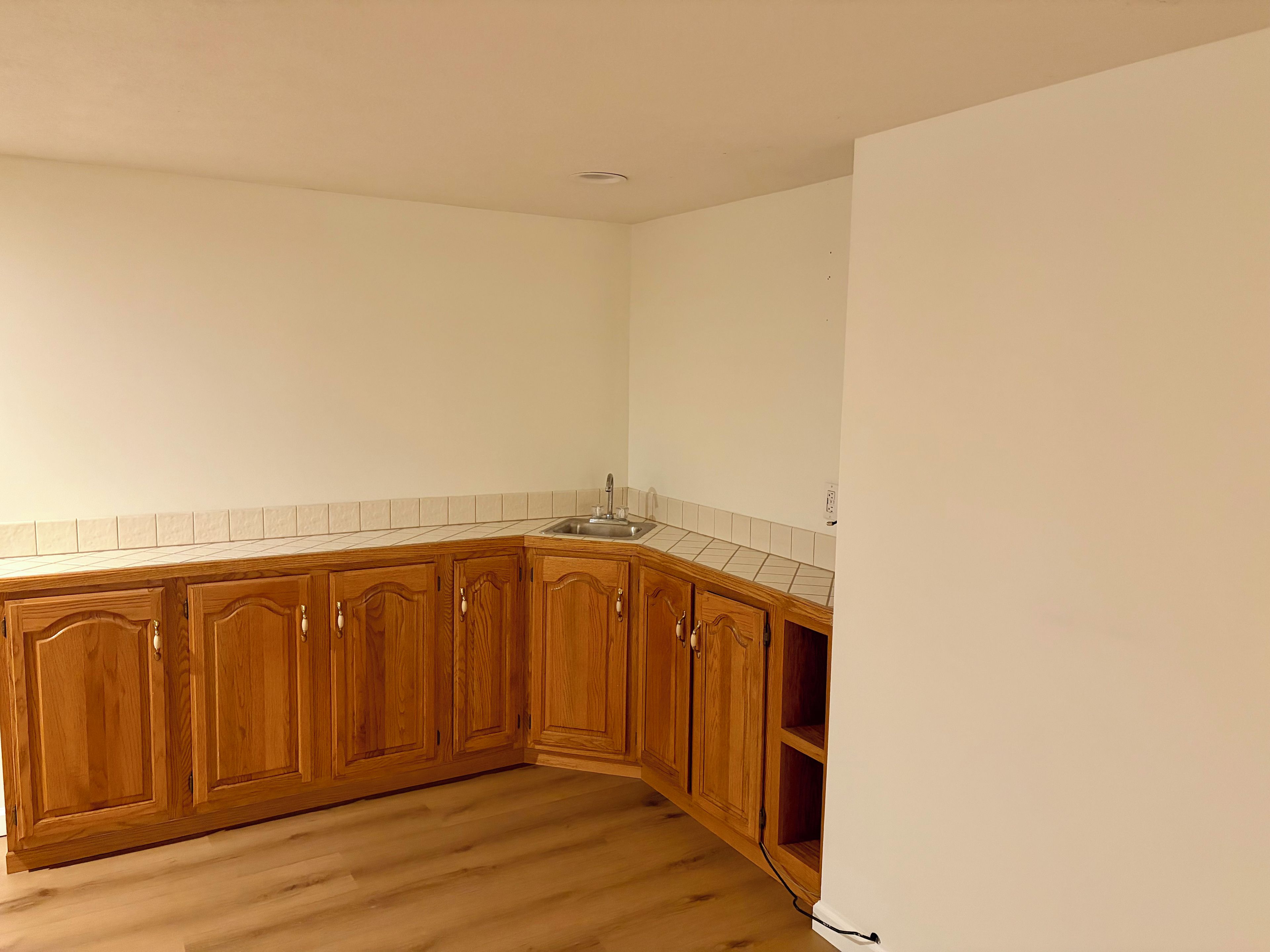A kitchen with wooden cabinets, a tiled backsplash, and a wooden floor.