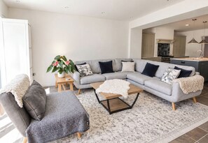 A modern living room with a sectional sofa, a coffee table, and a small side table with a plant. - Rheidiol (Haverfordwest)