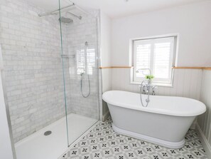 A bathroom with a glass-enclosed shower, a freestanding bathtub, and a window with blinds. - Rheidiol (Haverfordwest)