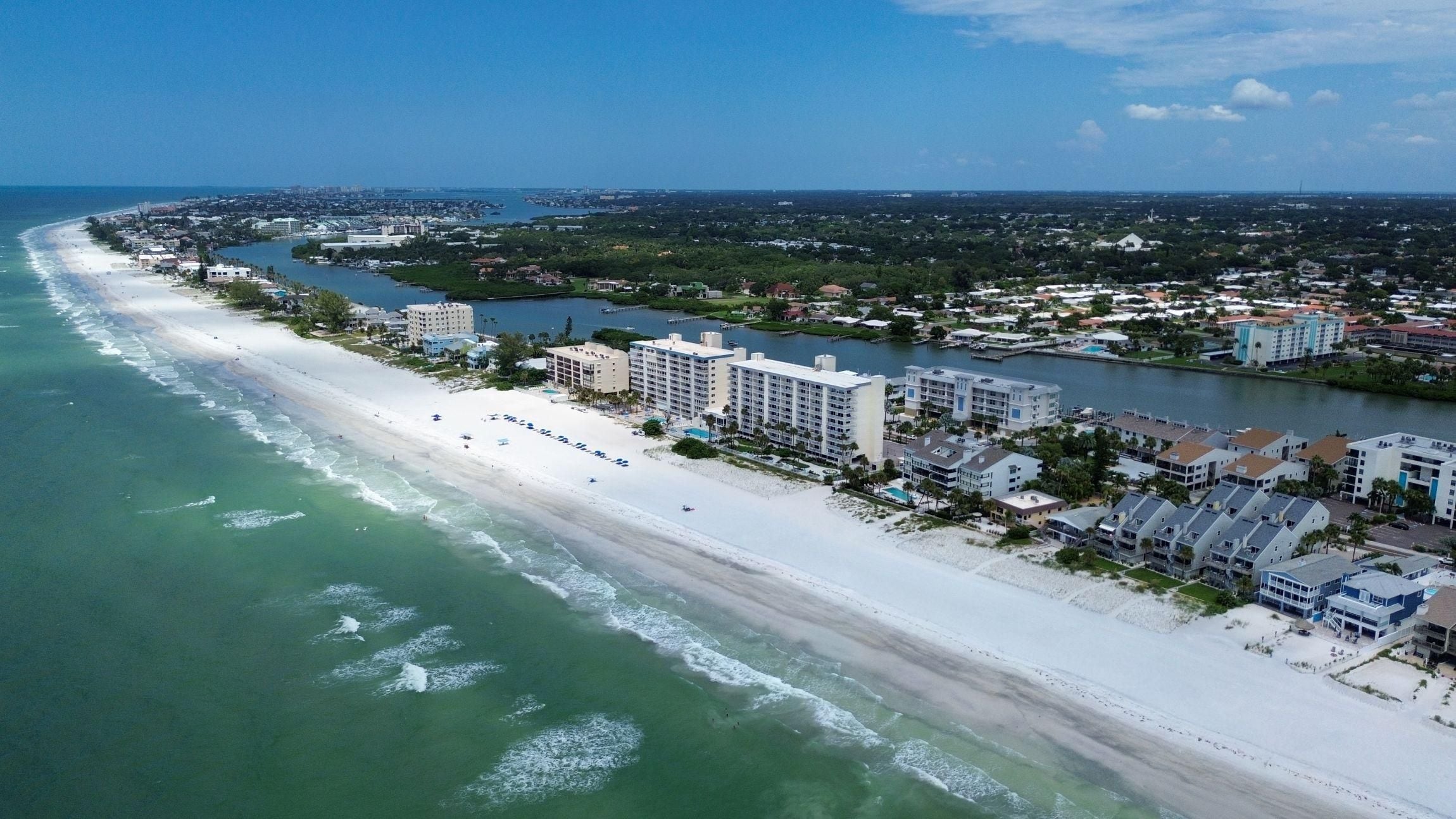 A coastal cityscape with a beach, a river, and a mix of residential and commercial buildings.