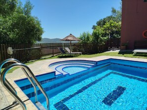A swimming pool with a wooden fence, a bench, and a lifebuoy. - Hierbabuena Apartment – Perfect for Families (Vejer de la Frontera)