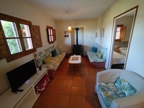 A cozy living room with a sofa, a television, a table, and a fireplace. - Hierbabuena Apartment – Perfect for Families (Vejer de la Frontera)