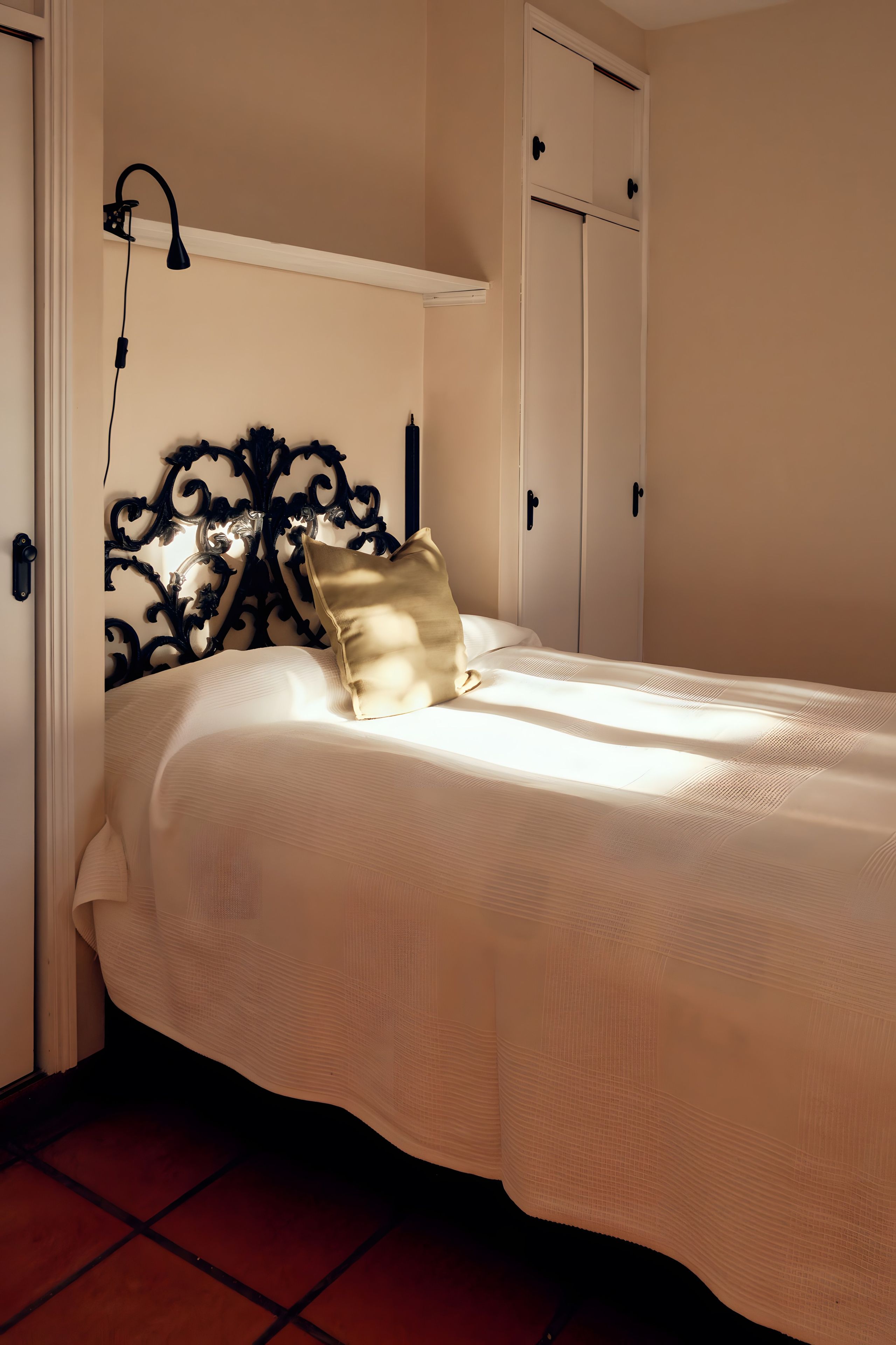 Un dormitorio con cama, mesita de noche, lámpara de pared y armario.