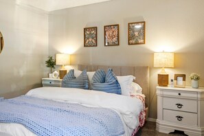 A bedroom with a bed, nightstands, a headboard, and wall-mounted lamps. - Cozy Duplex by Portal Park | Pet Friendly (Colorado Springs)
