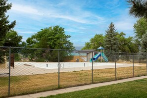 Ein umzäunter Spielplatz mit Rutsche und Kletterbereich.
