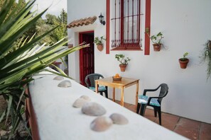 Eine Terrasse mit Tisch, Stühlen, Topfpflanzen und einer roten Tür.