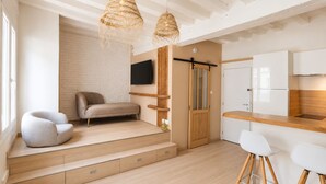 A modern interior with a sofa, a dining area, and a kitchen. - Harmoni Studio (Chartres)