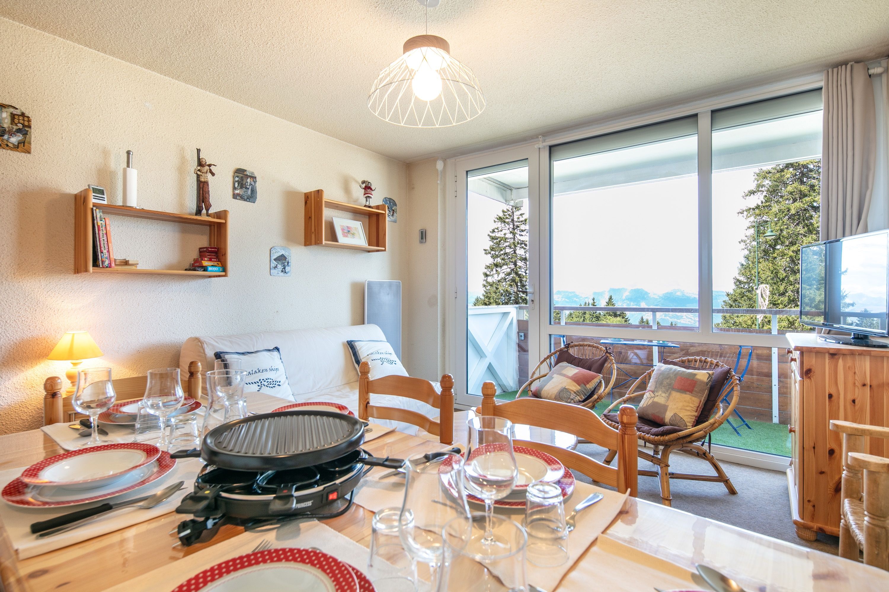 A dining area with a table set for a meal, chairs, a grill, and a view of the outdoors.