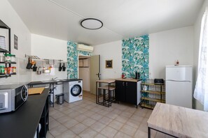 Una cucina compatta con lavatrice, lavello, un piccolo tavolo da pranzo e frigorifero.