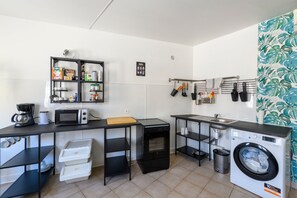 Eine kleine Küche mit Mikrowelle, Kaffeemaschine und Waschmaschine.