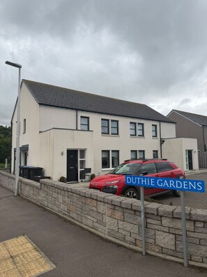 A modern two-story building with a red car parked in front. - Duthie Gardens Retreat – Peterhead (Aberdeenshire)