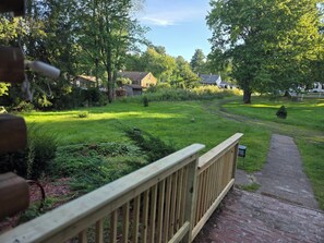 A wooden deck leading to a grassy yard with a brick pathway.