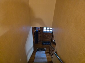 A wooden staircase with a handrail, leading to a landing with a wooden door and a window.