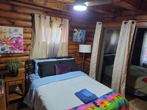 Een houten kamer met een bed, gordijnen, een lamp en een schilderij.