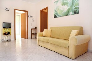 A living room with a sofa, a television, and a painting on the wall. - Adriana Sicily House Etna & Sea Parking (Acireale)
