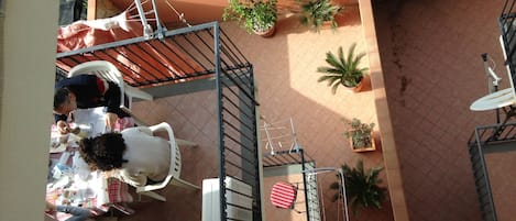 A rooftop terrace with a dining area, potted plants, and a satellite dish.