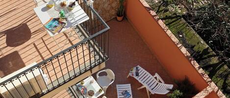 A rooftop terrace with a table, chairs, and a potted plant.