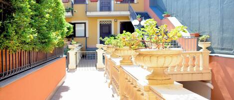 Un estrecho callejón con una fila de macetas y un edificio con balcones.
