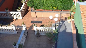 Eine Dachterrasse mit Blumentöpfen, einem Metallgeländer und einer grünen Wand.