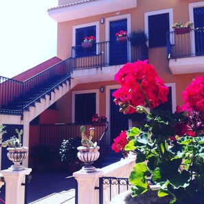 Ein Gebäude mit einer Treppe, Balkonen mit Blumenkästen und Topfpflanzen.