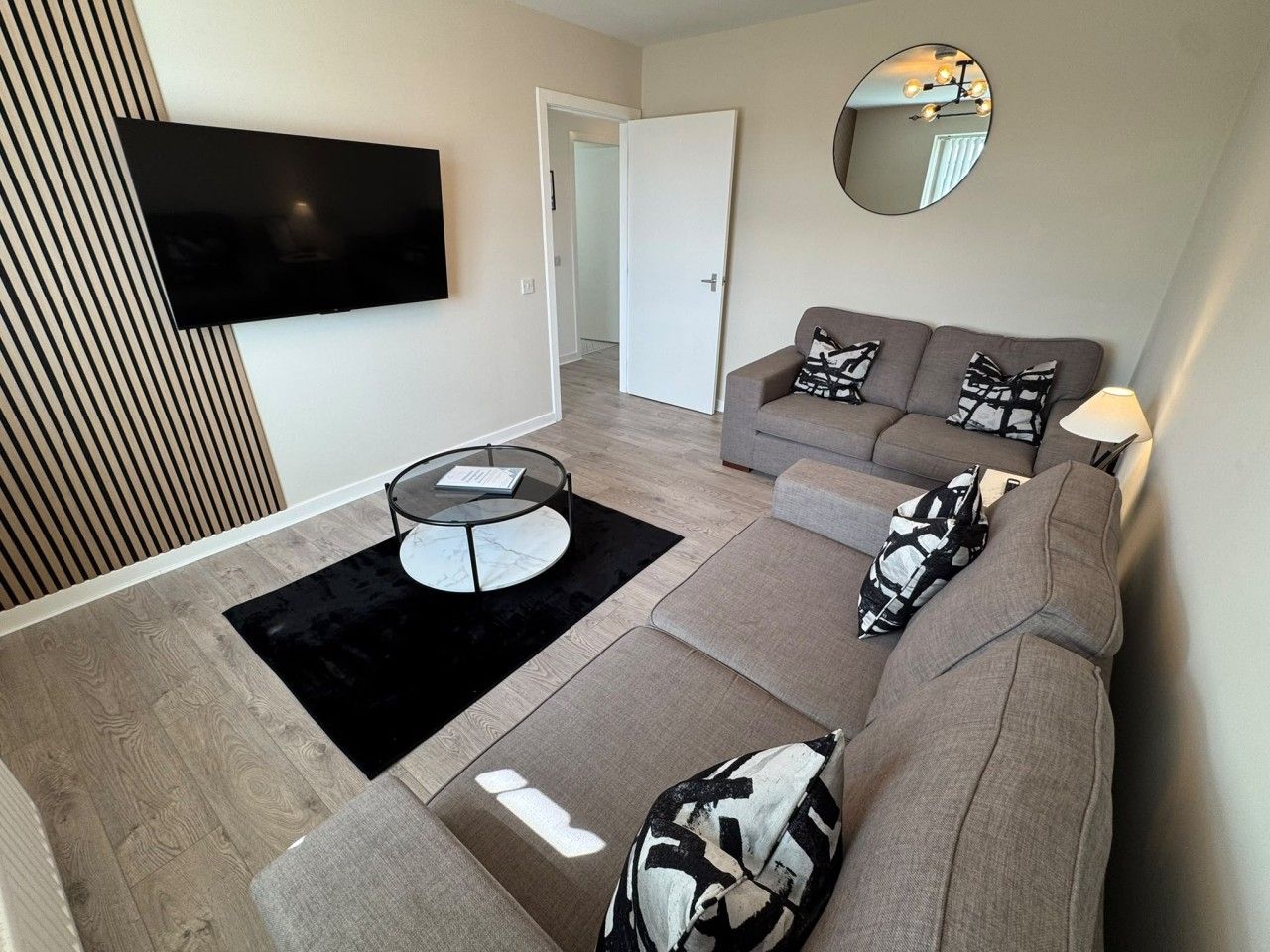 A modern living room with a sofa, a coffee table, and a flat-screen TV mounted on the wall.
