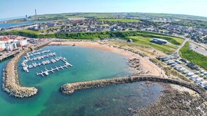 An aerial view of a coastal area with a marina, residential buildings, and industrial facilities.