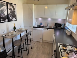 A modern kitchen with white cabinets, a dishwasher, a microwave, and a gas stove.