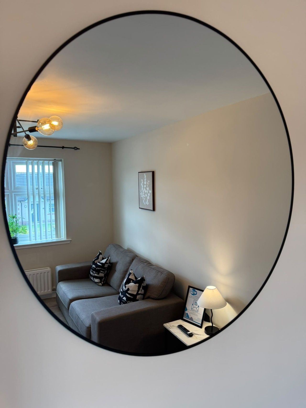 Un salon avec un canapé, une lampe et un tableau encadré au mur.
