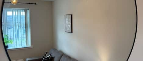 Una sala de estar con un sofá, una lámpara y un cuadro enmarcado en la pared.