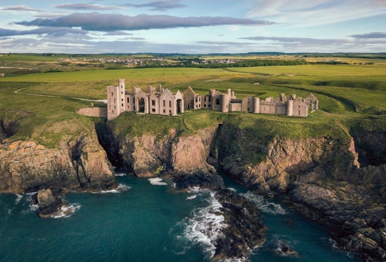 A coastal castle with multiple towers, situated on a cliff overlooking the sea.