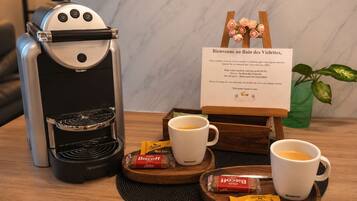A coffee machine, two cups of coffee, a menu sign, and some snacks on a table.