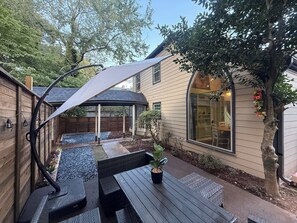 Eine Terrasse mit Tisch, Stühlen, einem Blumentopf und einem Holzzaun.