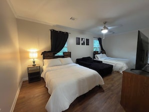 Ein Hotelzimmer mit zwei Betten, einem Schreibtisch, einem Fernseher und einem Deckenventilator.