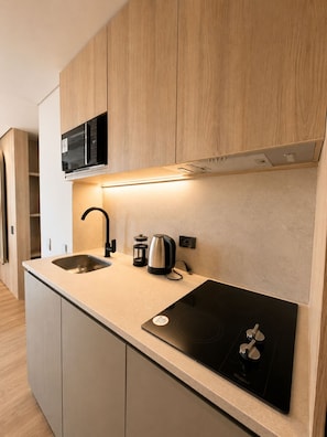 Una cocina moderna con microondas integrado, hervidor y fogones.