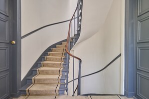 A spiral staircase with a wooden handrail and beige carpeted steps. - Charming Apartment Montaigne Champs Elysees (Paris)
