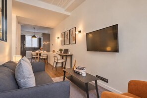 A modern living room with a sofa, a coffee table, and a TV mounted on the wall. - Charming Apartment Montaigne Champs Elysees (Paris)