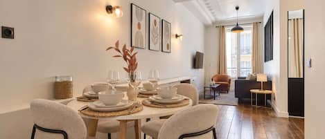 A dining area with a round table set for four, surrounded by chairs.