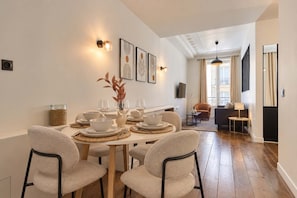A dining area with a round table set for four, surrounded by chairs. - Charming Apartment Montaigne Champs Elysees (Paris)