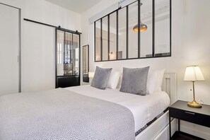 A modern bedroom with a bed, bedside tables, a lamp, and a large mirror. - Charming Apartment Montaigne Champs Elysees (Paris)