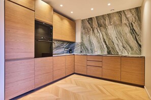 Eine moderne Küche mit Holzschränken, einem eingebauten Backofen und einer Marmor-Spritzschutzwand.