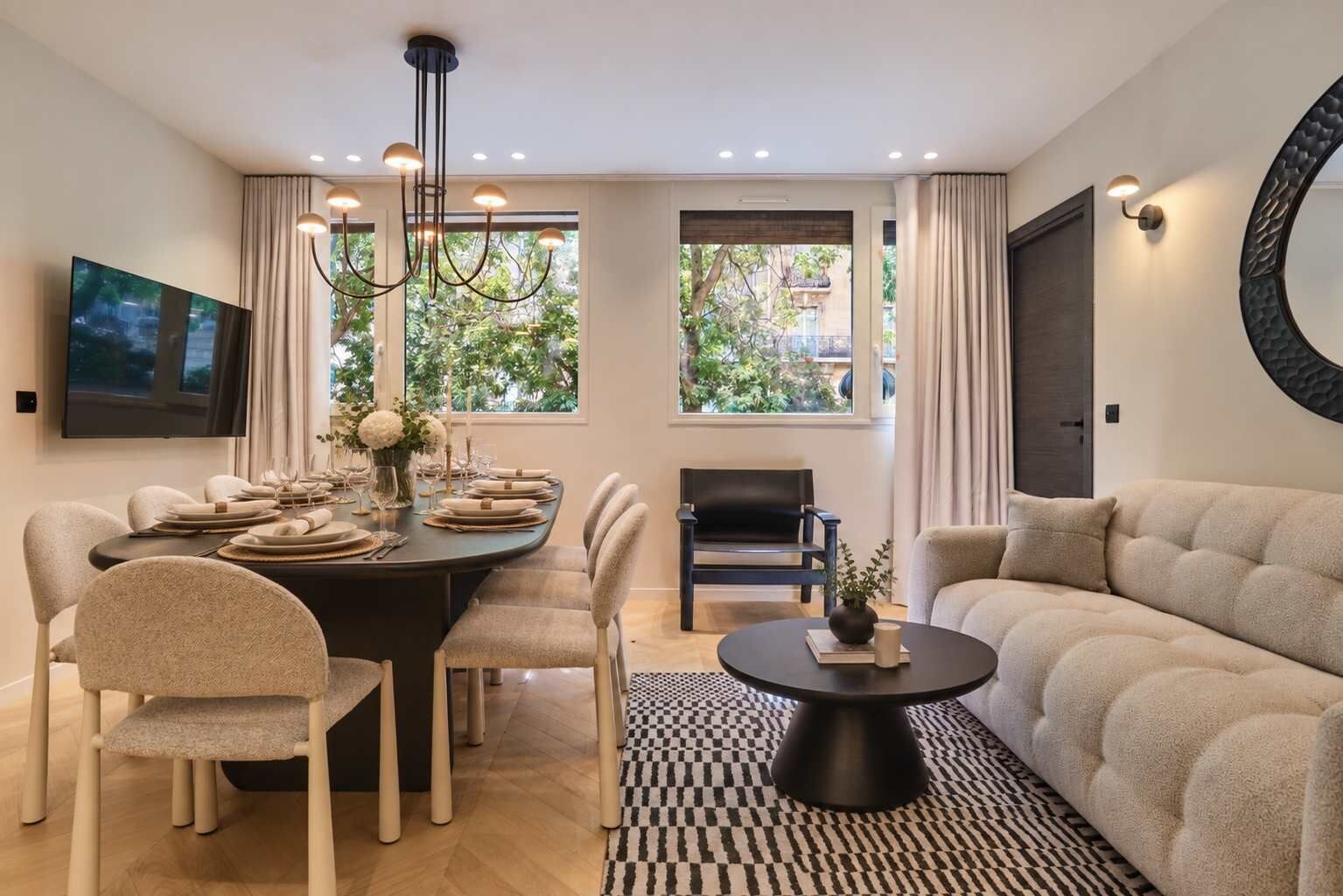 Un salon moderne avec un canapé, une table à manger dressée pour quatre personnes et une table basse.