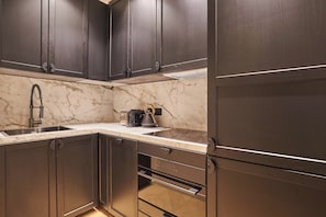 A modern kitchen with dark cabinetry, a marble countertop, and stainless steel appliances. - Sublim Apartment AC St Germain Luxembourg Park (Paris)