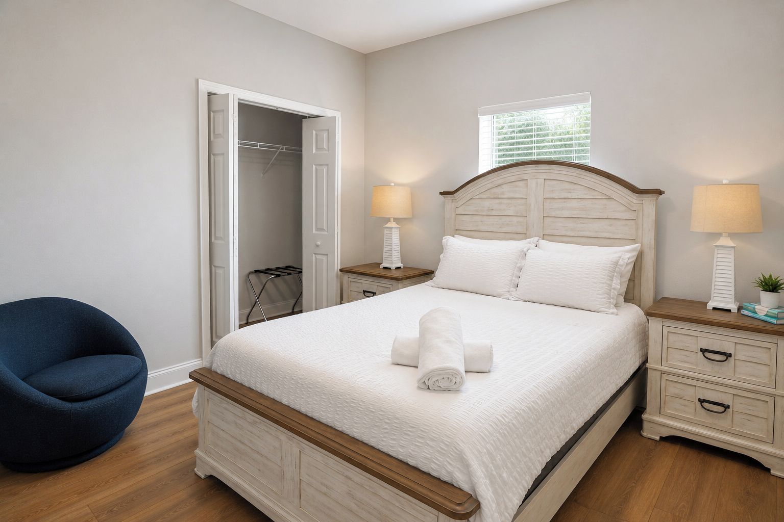 Une chambre à coucher comprenant un lit, des tables de chevet, une chaise et un dressing.