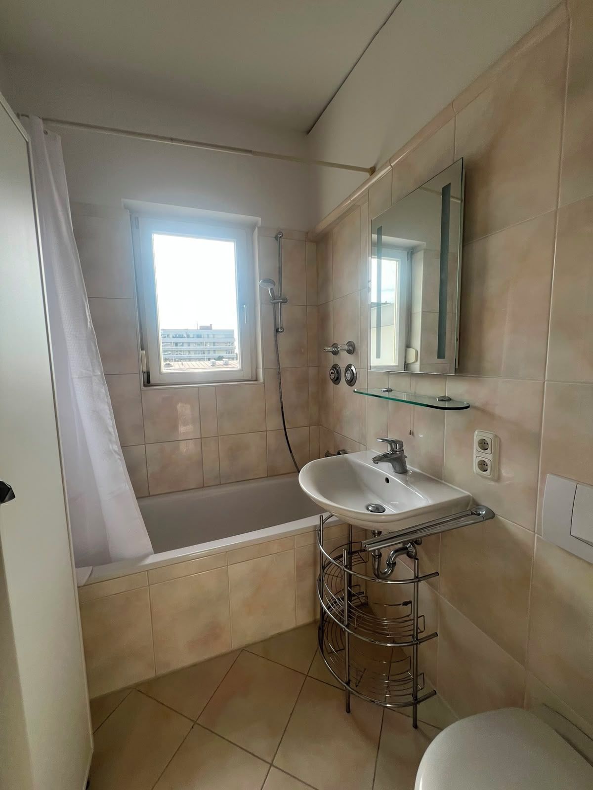 Ein Badezimmer mit einer Badewanne, einem Waschbecken, einem Spiegel und einem Fenster.