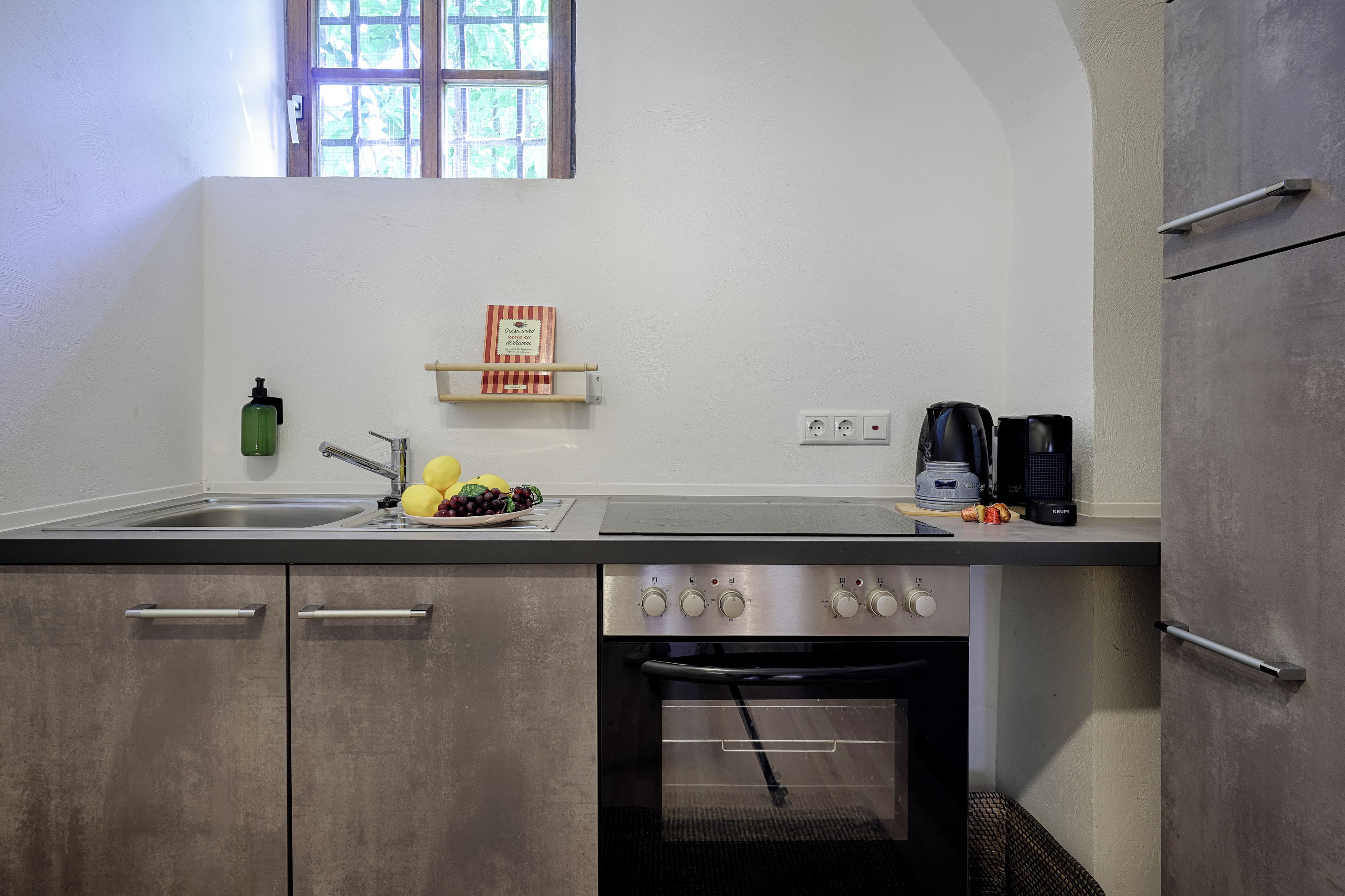 A kitchen with a sink, a stove, and a window above the counter.