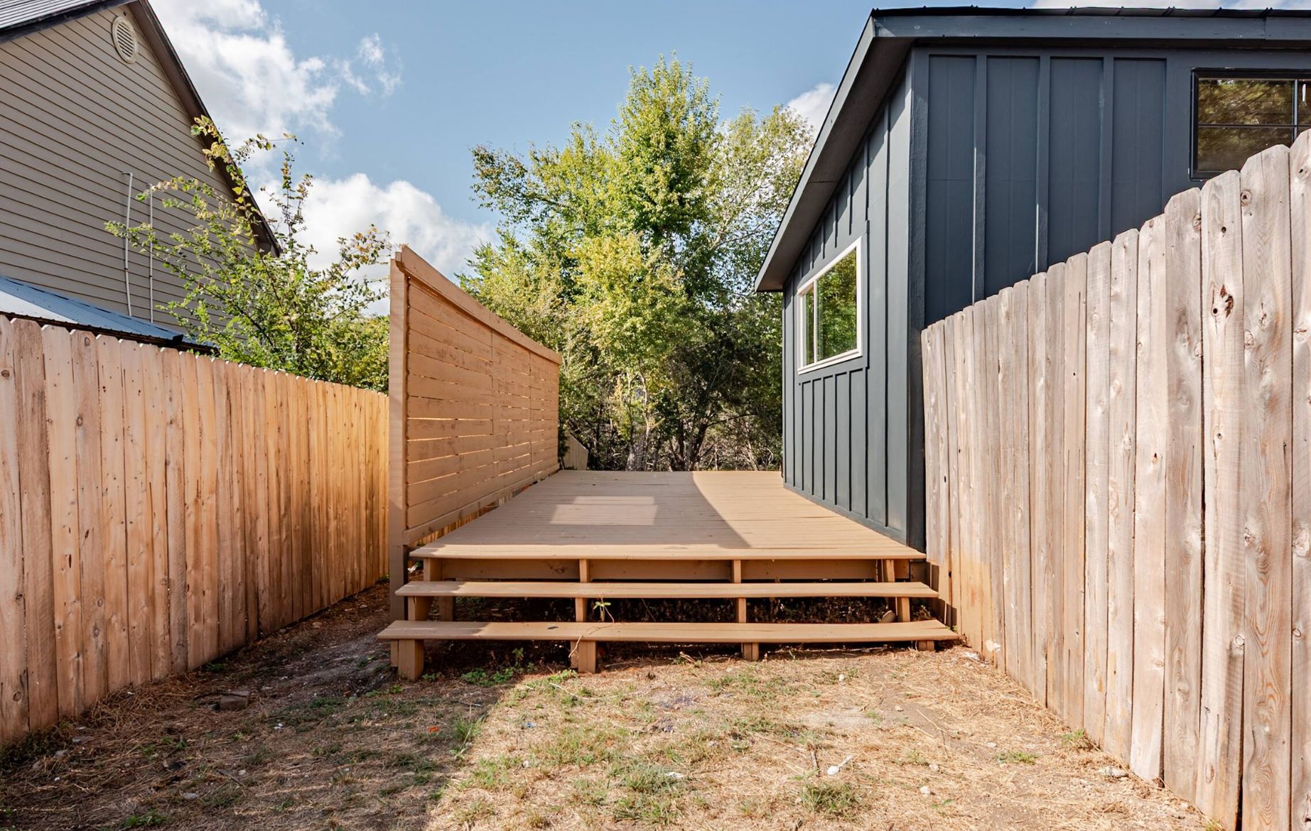 A backyard with a wooden deck, a shed, and a fence.