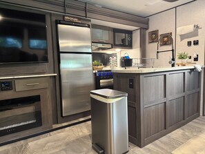 A modern kitchen with stainless steel appliances, a built-in oven, and a central island with a sink. - Adventure Awaits! Come Camp, Glamp, and RV with us! Golf cart included! (Corbin)