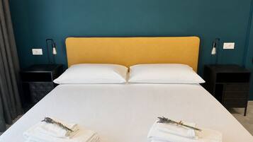 Une chambre d’hôtel avec un lit, deux tables de chevet et une paire de serviettes parfumées à la lavande.